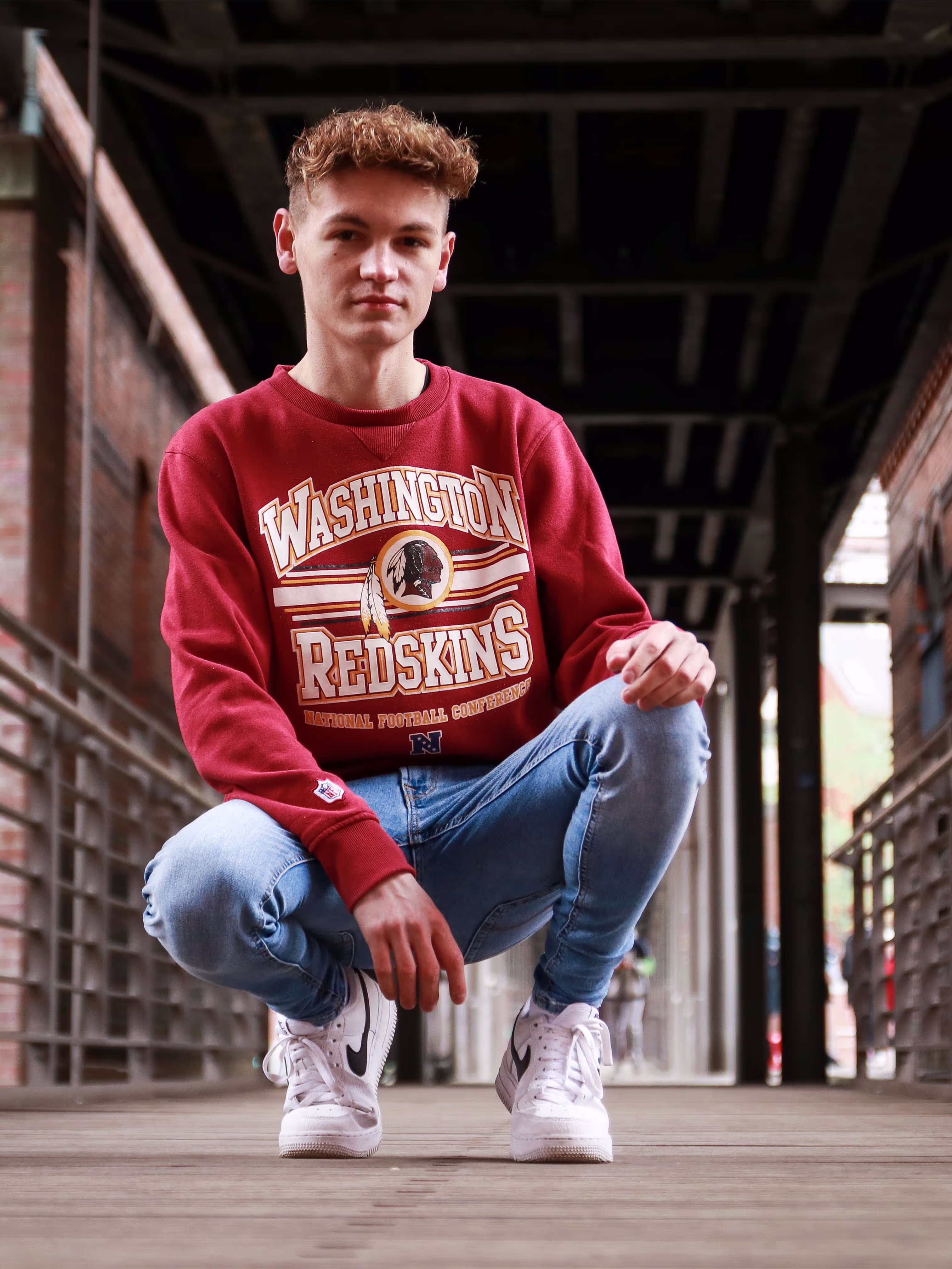 Dylan squatting on a bridge.